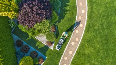 Gardener landscaping garden with mower