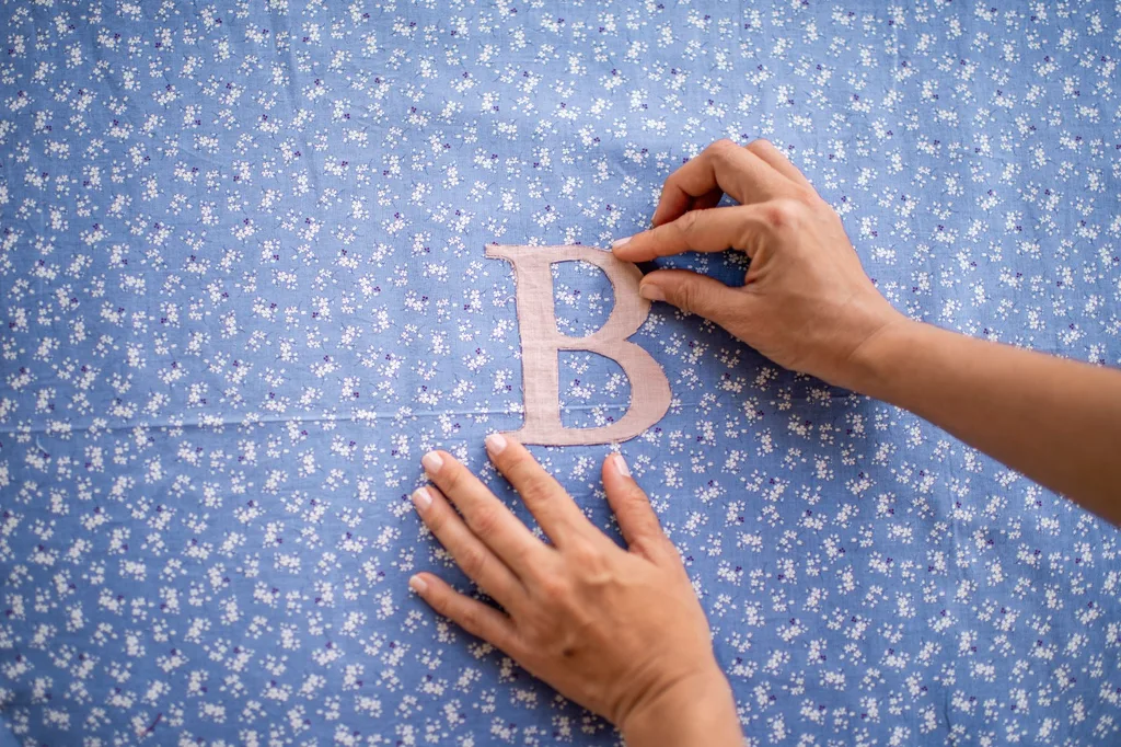 mãos alinhando a letra 'b' em tecido paisley