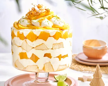 mango trifle filled with homemade mango jelly, coconut cream, linme and piled high above the trifle dish
