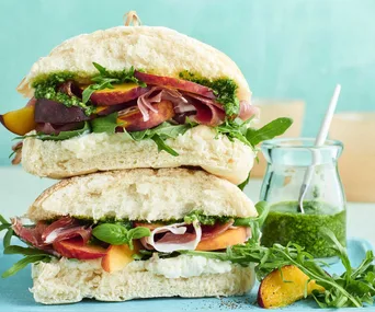 Peach, proscuitto and pesto sandwich on a blue tray
