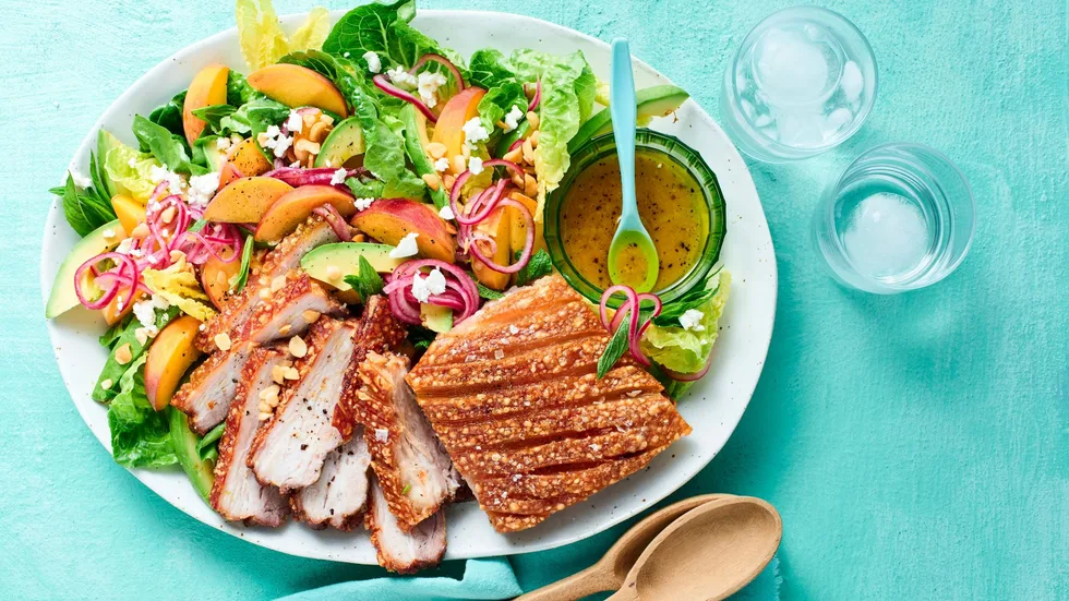 Airfryer pork belly and peach salad with ice water and wooden serving spoons