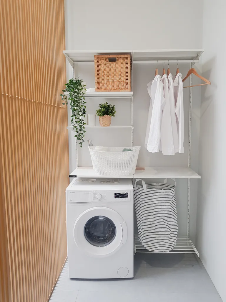 laundry room with hanging plants, cane basket, hanging white linen shirts and wooden panel wall