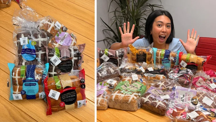 wooden table with 5 packets of supermarket hot cross buns slashed with image of woman holding up hands and smiling behind full table of hot cross buns