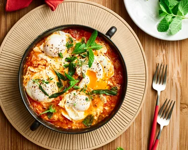 lamb shakshuka with eggs cooked in tomato sauce with fresh herbs on top of bowl
