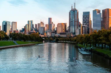 melbourne CBD in late afternoon with yarra river and two boats kayaking along it