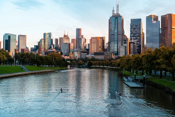 melbourne CBD in late afternoon with yarra river and two boats kayaking along it