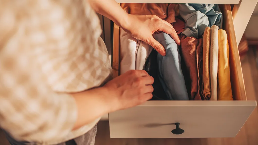 Person opening drawer and organising clothing