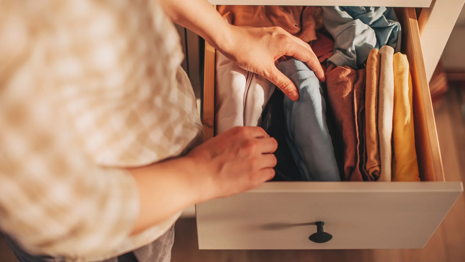 Person opening drawer and organising clothing