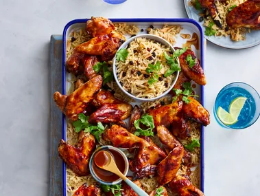 air fryer chicken wings on rectangular tray with rice pilaf underneath and in bowl in the centre