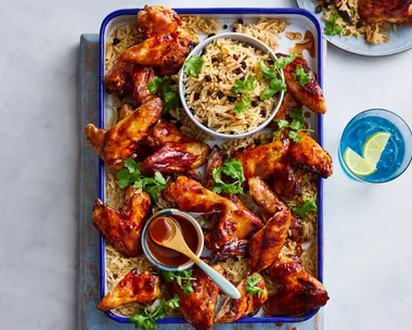 air fryer chicken wings on rectangular tray with rice pilaf underneath and in bowl in the centre