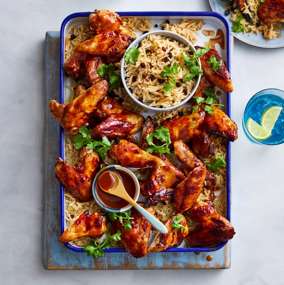 air fryer chicken wings on rectangular tray with rice pilaf underneath and in bowl in the centre