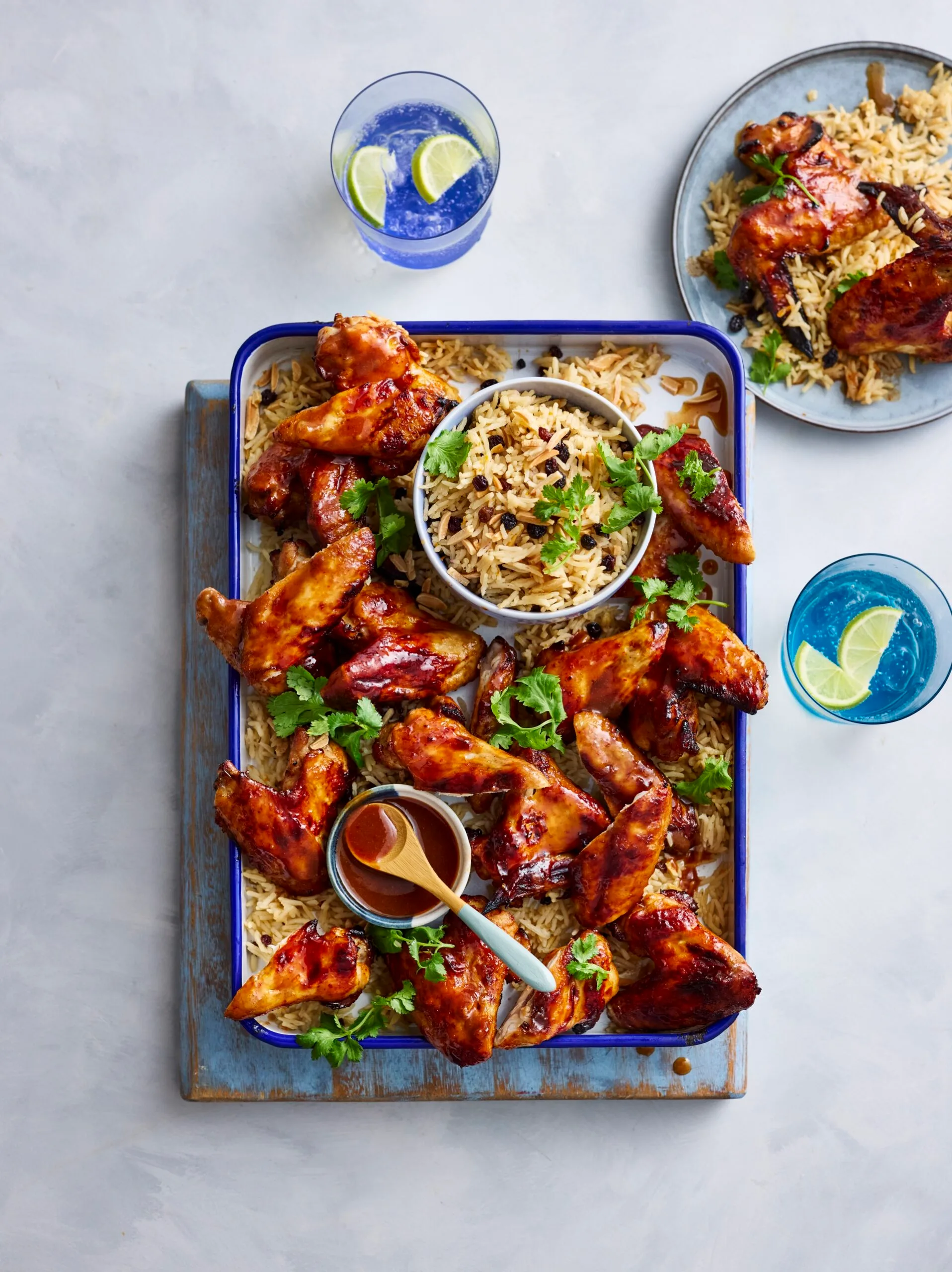 air fryer chicken wings on rectangular tray with rice pilaf underneath and in bowl in the centre