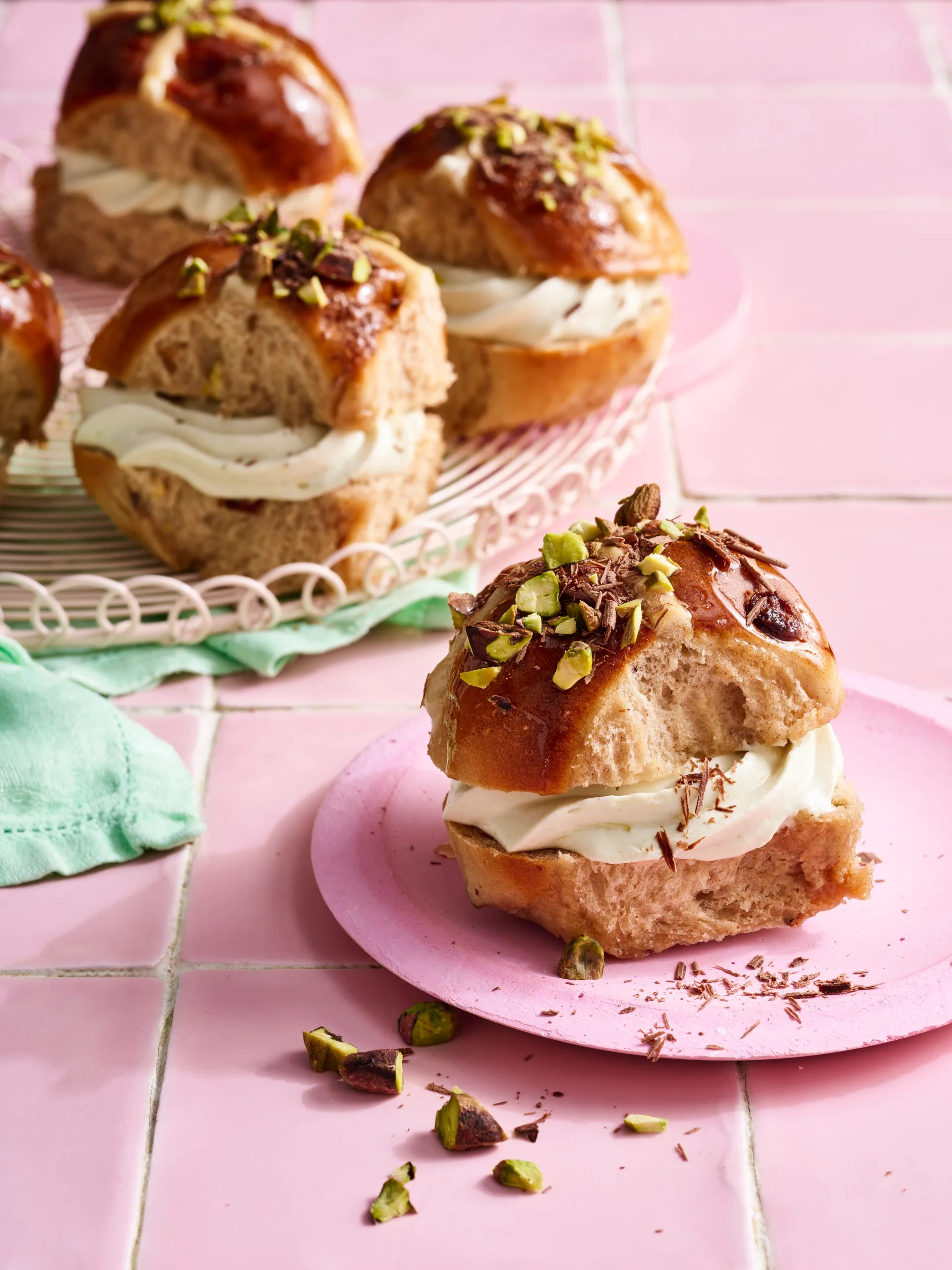 air fryer hot cross buns with pistachio and chocolate frosting filling and sprinkled nuts on top
