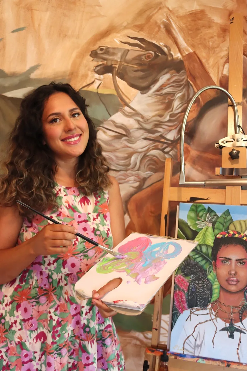 Artist Brandi Salmon with her work in the foreground and background