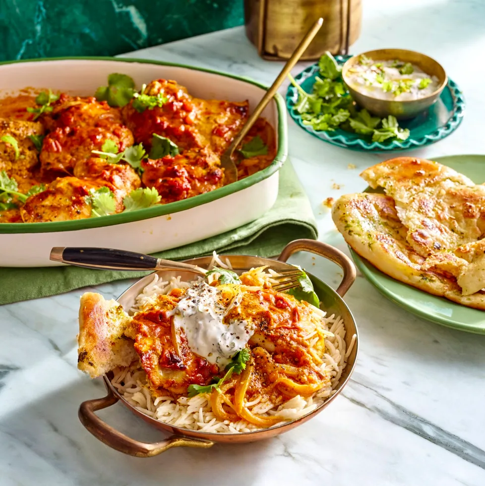 easy butter chicken traybake one pan butter chicken in the over in small dish with handles and mint yoghurt on top
