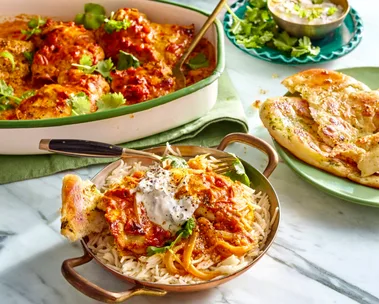easy butter chicken traybake one pan butter chicken in the over in small dish with handles and mint yoghurt on top