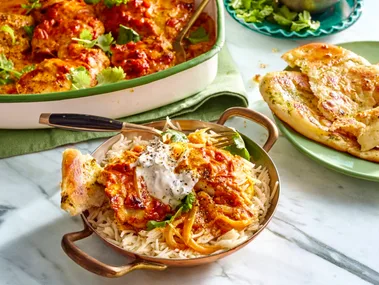 easy butter chicken traybake one pan butter chicken in the over in small dish with handles and mint yoghurt on top