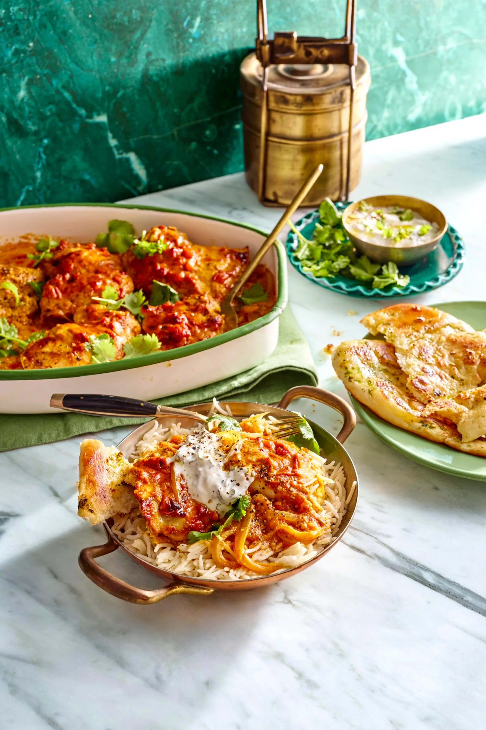easy butter chicken traybake one pan butter chicken in the over in small dish with handles and mint yoghurt on top