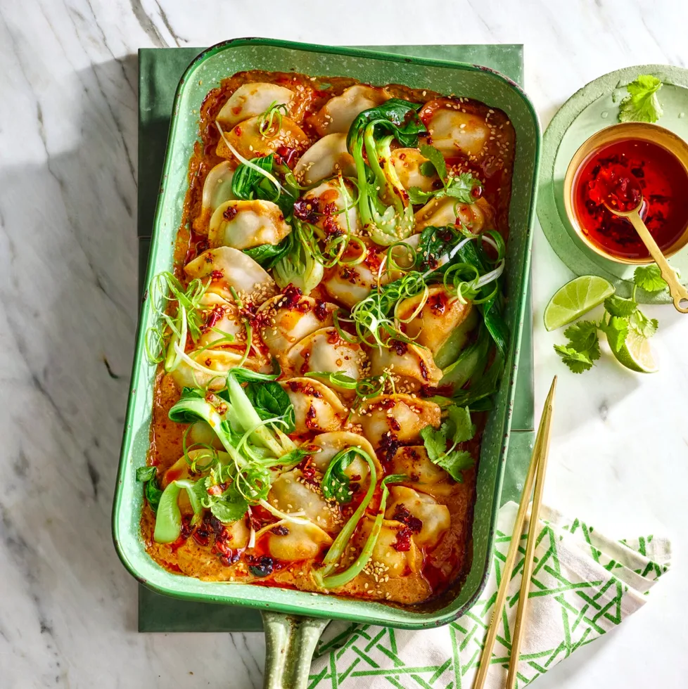 dumpling dump and bake with spring onion on top in a large baking dish with gold handle