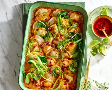 dumpling dump and bake with spring onion on top in a large baking dish with gold handle