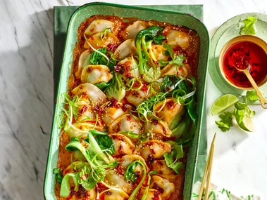 dumpling dump and bake with spring onion on top in a large baking dish with gold handle