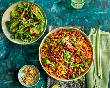 sticky mince beef noodles with asian herbs on top and mixed salad to the side