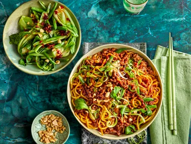 sticky mince beef noodles with asian herbs on top and mixed salad to the side