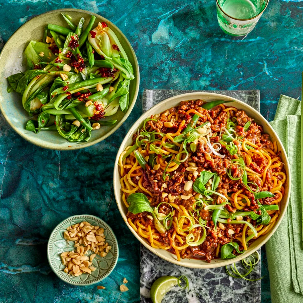 sticky mince beef noodles with asian herbs on top and mixed salad to the side