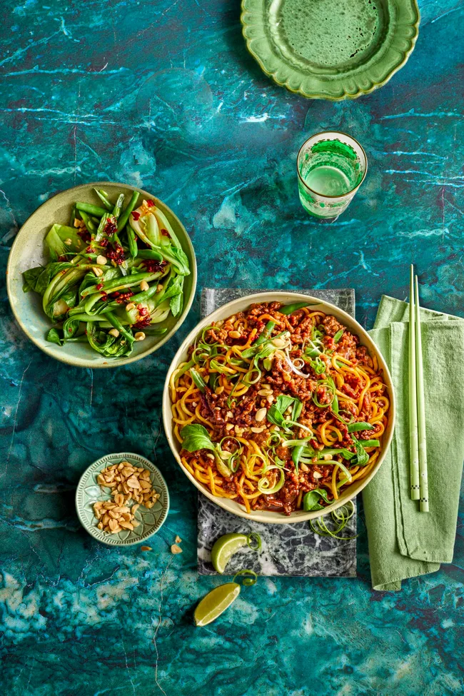 sticky mince beef noodles with asian herbs on top and mixed salad to the side