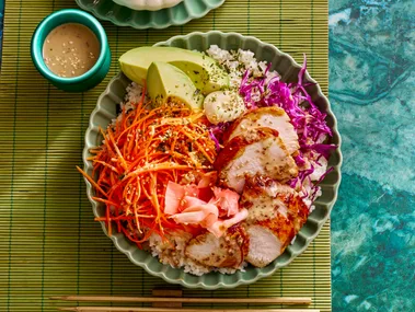 teriyaki chicken bowl with sushi rice shredded carrot pickled ginger and sesame dressing in small bowl on the side