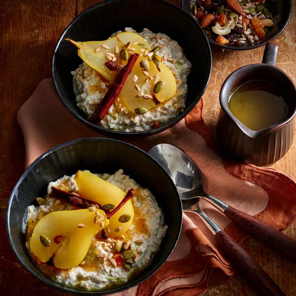 bircher muesli with poached pears in black bowls with red tablecloth and dark lighting