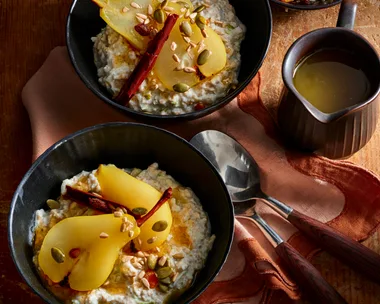 bircher muesli with poached pears in black bowls with red tablecloth and dark lighting