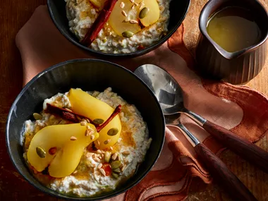 bircher muesli with poached pears in black bowls with red tablecloth and dark lighting