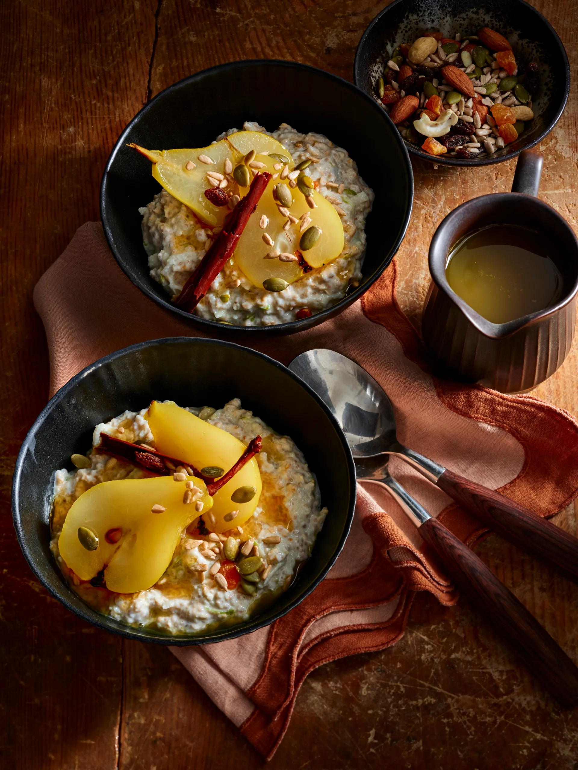 bircher muesli with poached pears in black bowls with red tablecloth and dark lighting