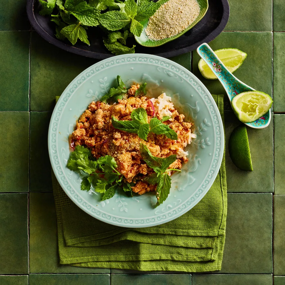 chicken larb in bowl with greens and blue bowl