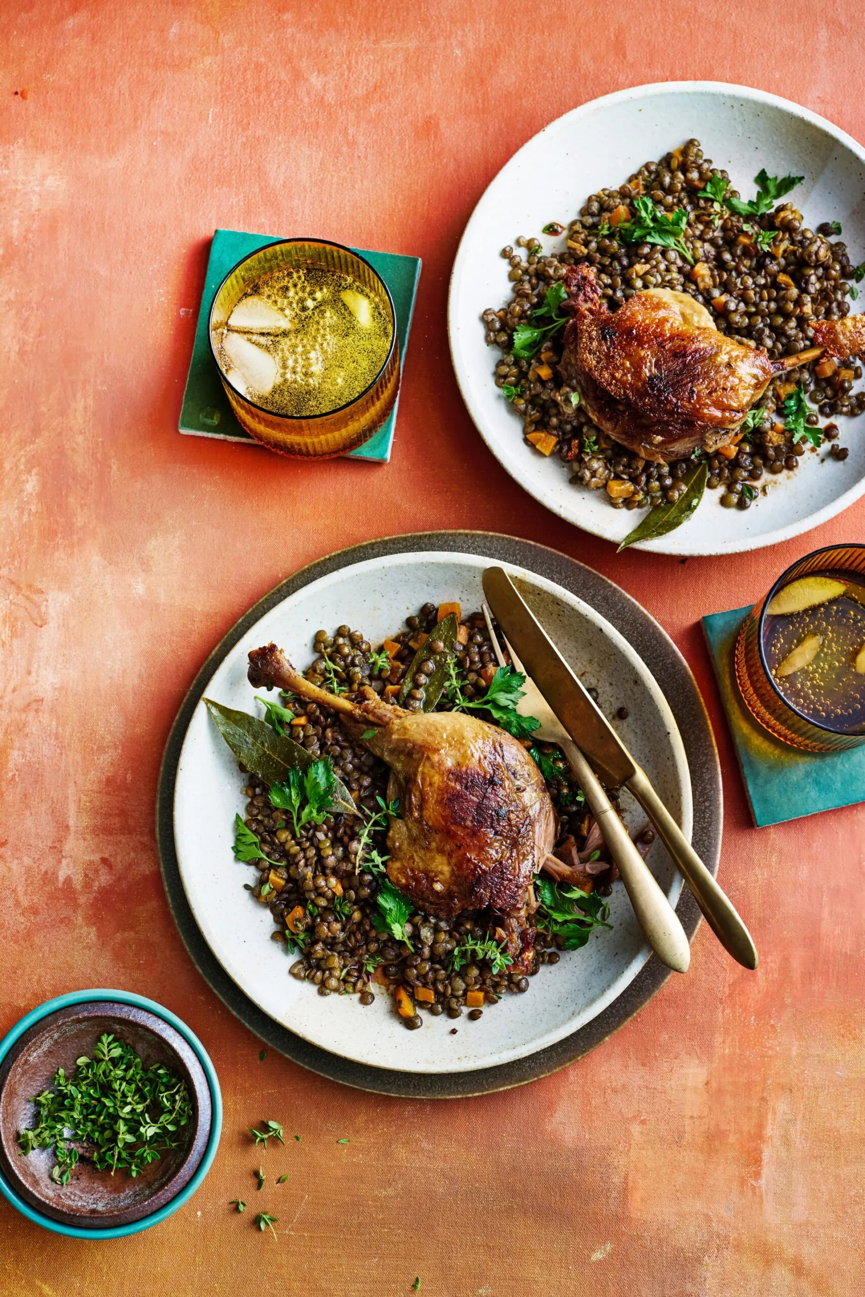 duck confit leg on top of french style lentils with white bowl underneath