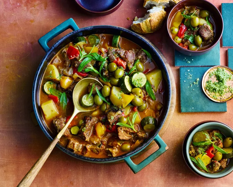 colin fassnidge's lamb ragu in giant bowl with wooden spoon and herbs on top