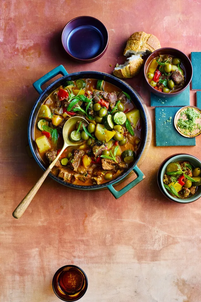 colin fassnidge's lamb ragu in giant bowl with wooden spoon and herbs on top