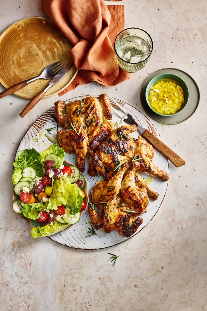 poussin with greek salad small chickens on plate with salad and dressing on the side