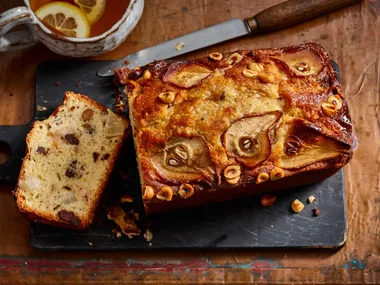 pear and chocolate loaf cake with pear and hazelnut indented on top and slice cut out to show cross section