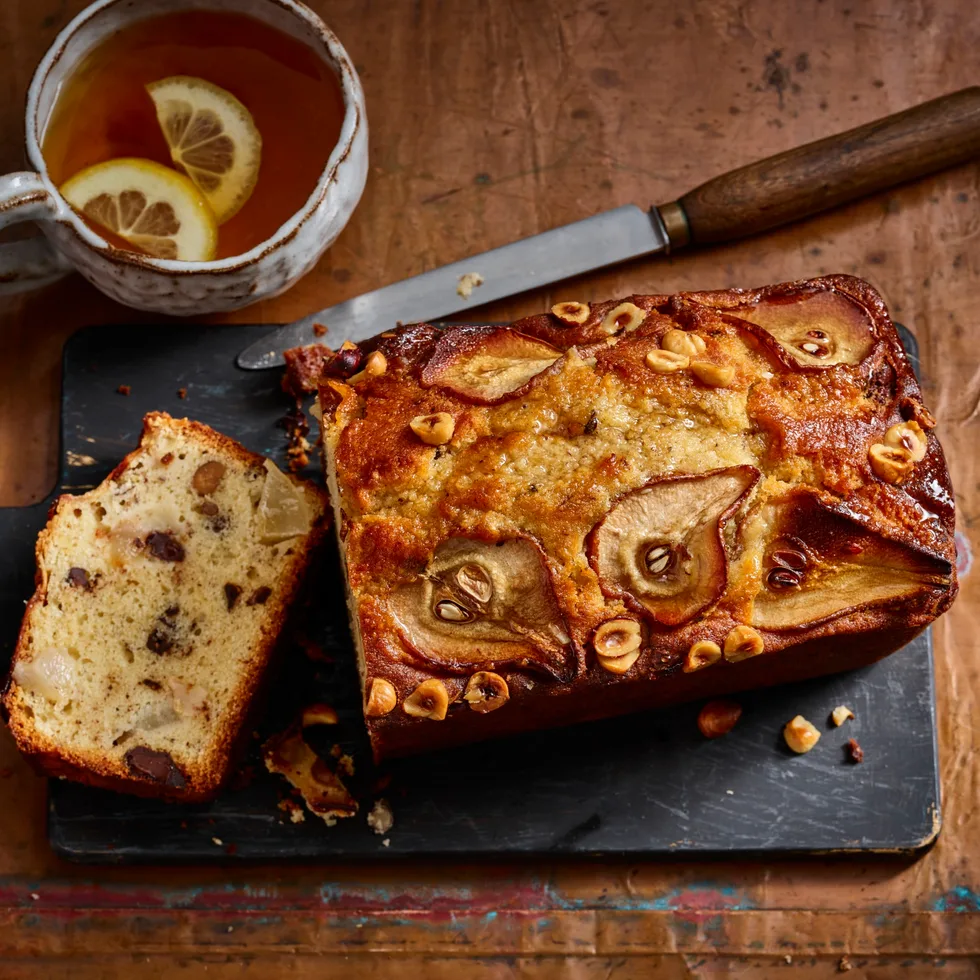 pear and chocolate loaf cake with pear and hazelnut indented on top and slice cut out to show cross section