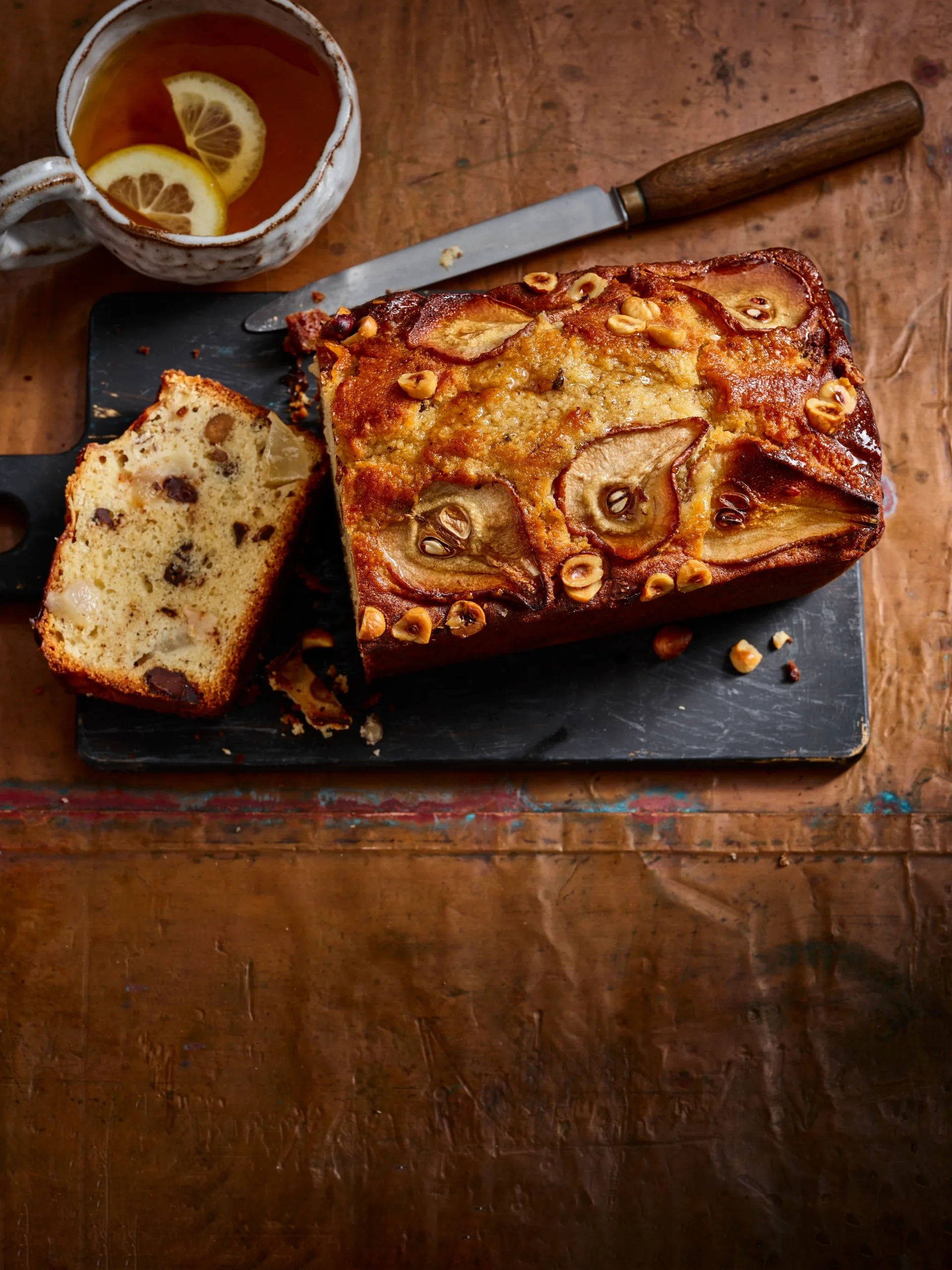 pear and chocolate loaf cake with pear and hazelnut indented on top and slice cut out to show cross section