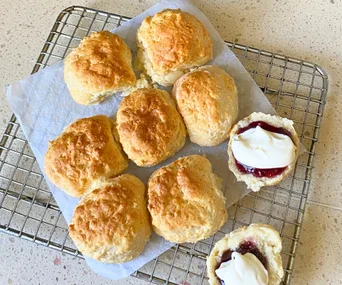 Air fryer lemonade scones on a cooling rack and topped with jam and cream