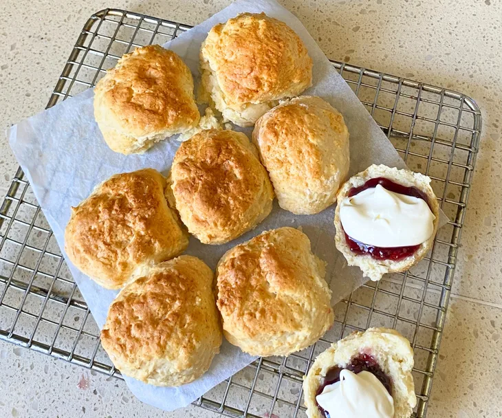 Air fryer lemonade scones on a cooling rack and topped with jam and cream
