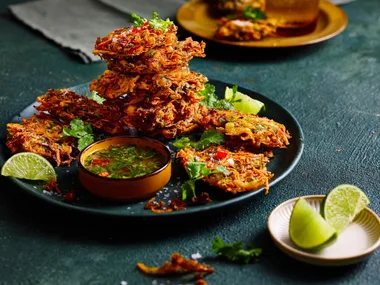 vegetable bhajis piled high on plate with slice of lime
