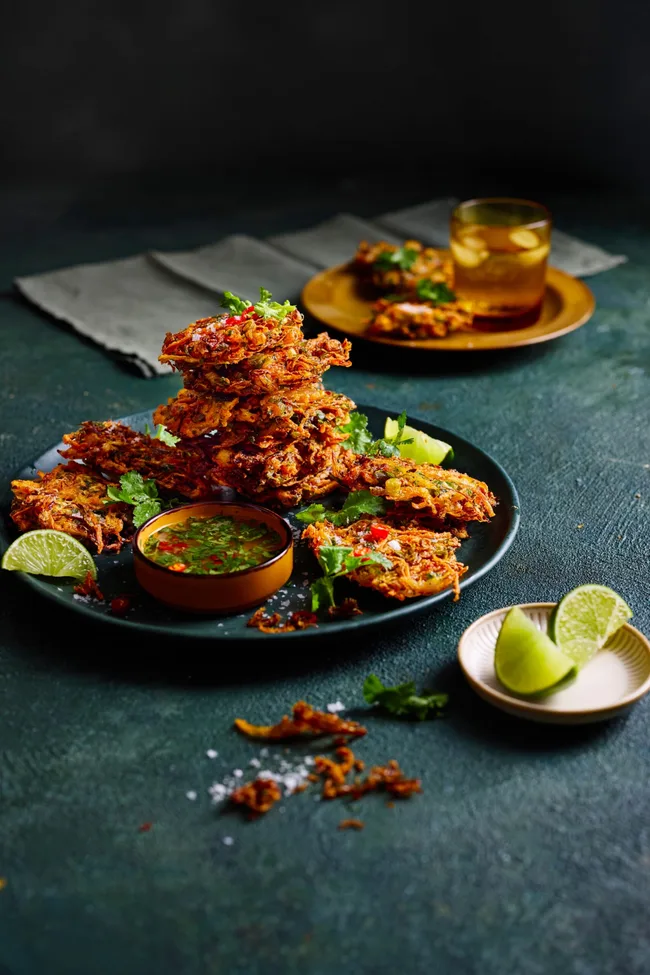 vegetable bhajis piled high on plate with slice of lime