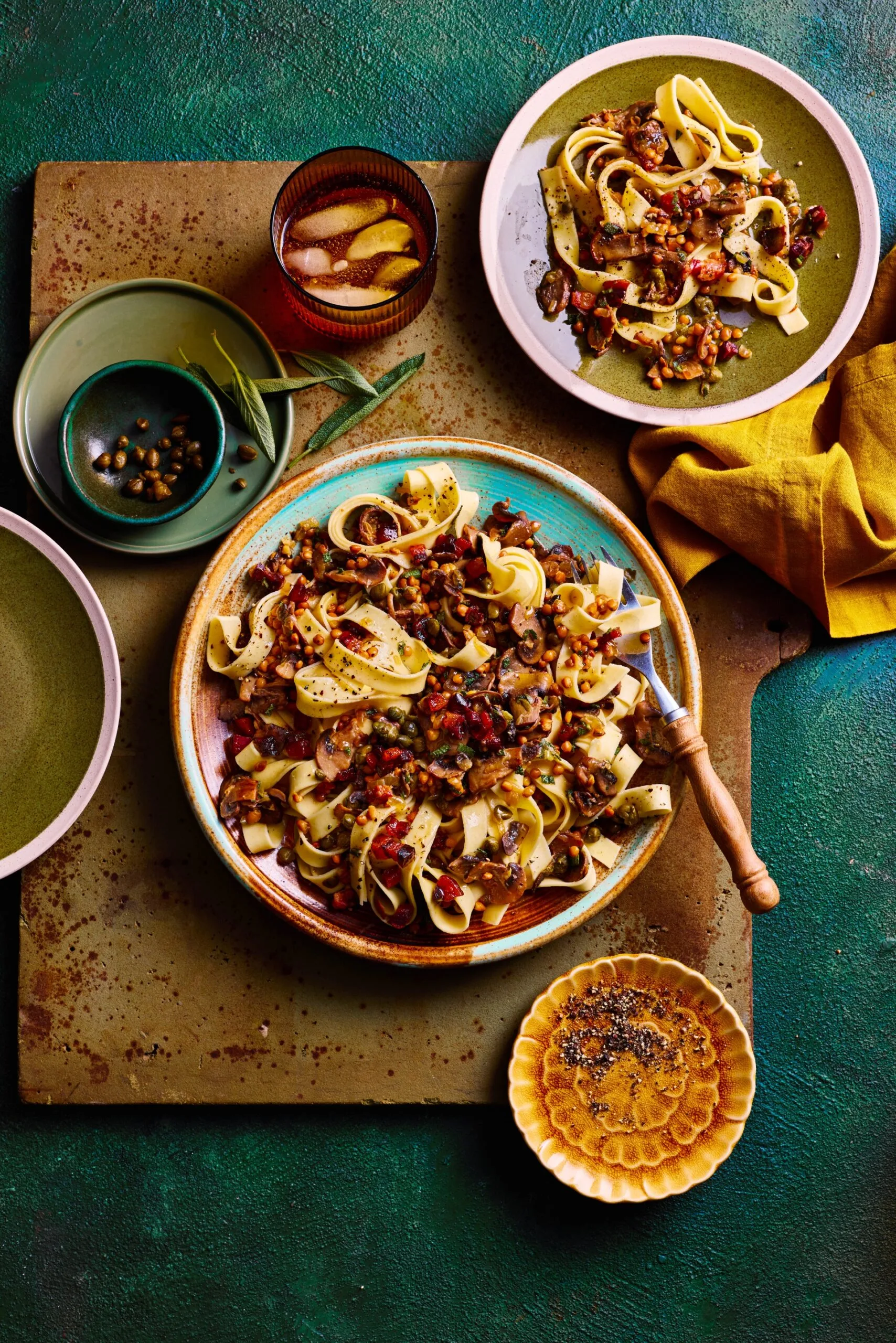mushroom sage and pancetta pasta in bowl with tagliatelle pasta and chopping board underneath