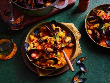 nduja mussels in pan with spoon sticking out and orange liquid sauce