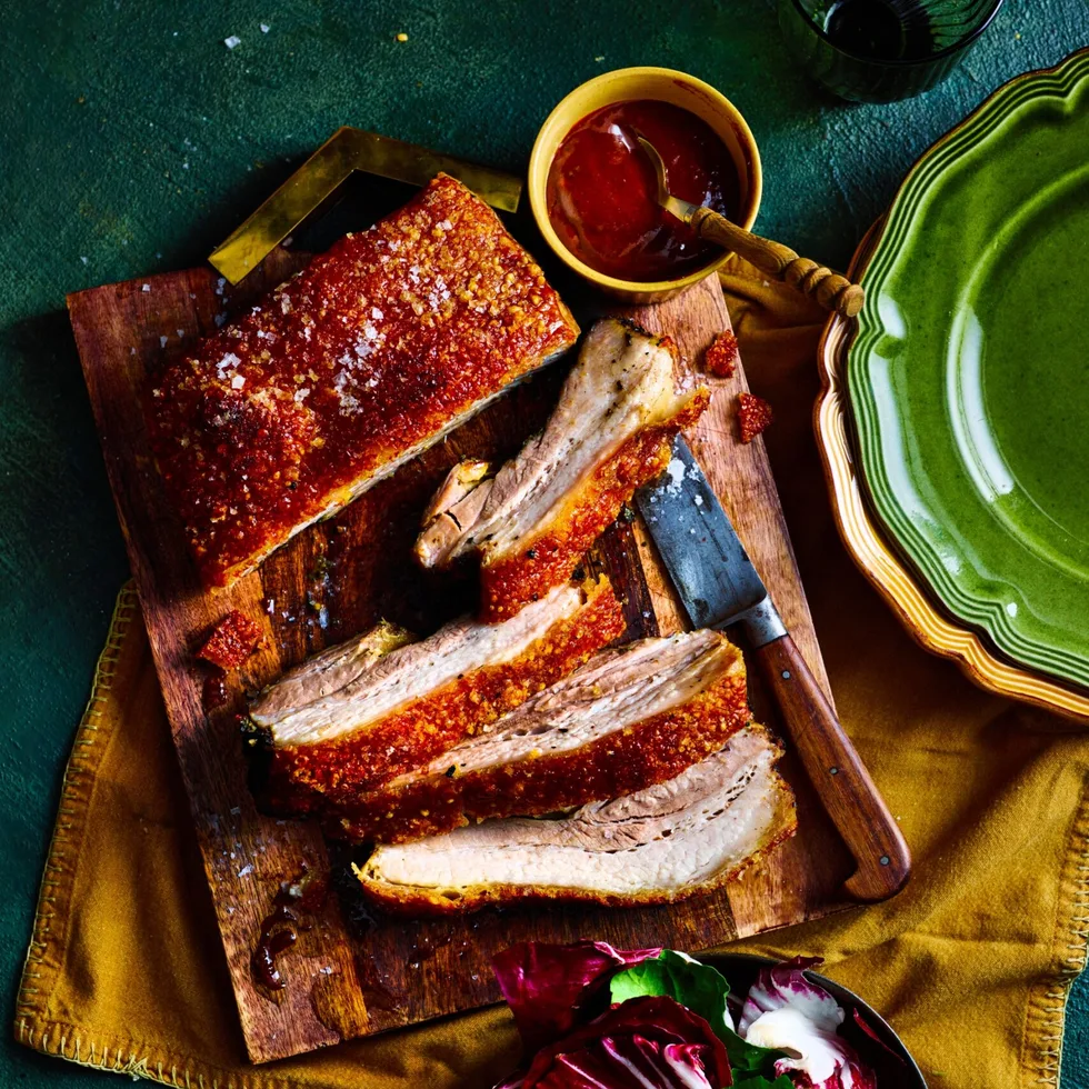 pork belly rotisserie recipe with huge slices cute into it and barbecue sauce on the side