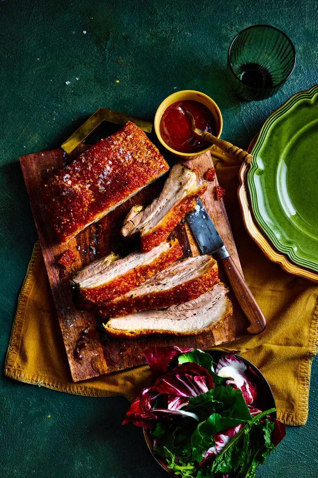 pork belly rotisserie recipe with huge slices cute into it and barbecue sauce on the side